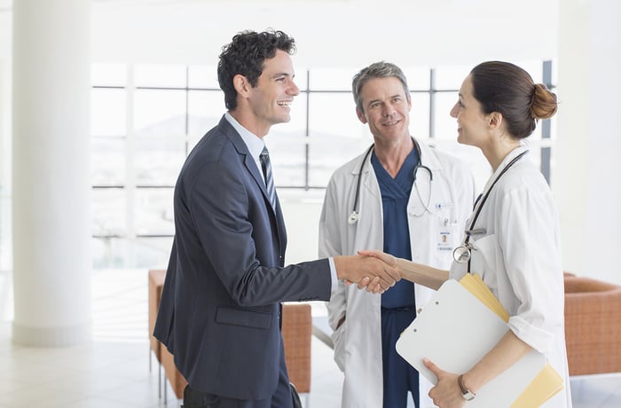 Doctor-businessman-handshaking-hospital-lobby-184312665